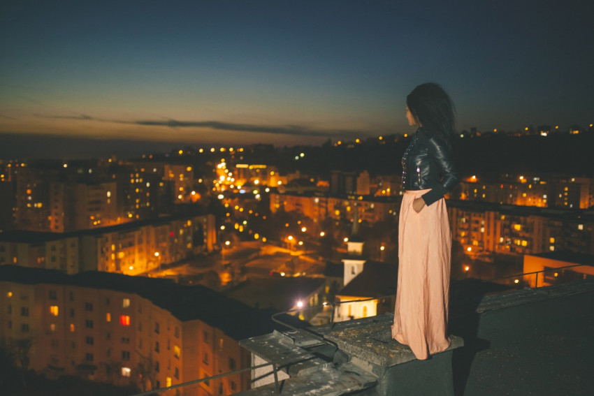 Девушка на крыше высокого здания смотрит на ночной город - Фотография -  PerfectStock